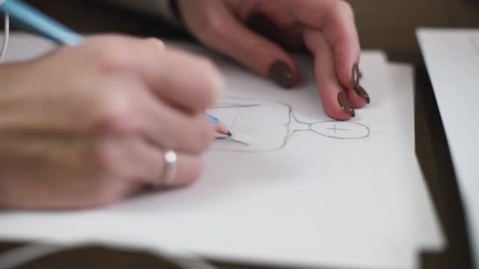 时装设计师为服装素描绘制模型。女裁缝的手在她的工作室的纸上绘制图案