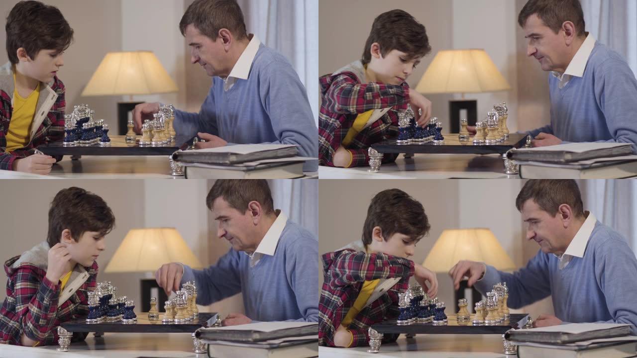 可爱的小高加索男孩在室内和祖父下棋的侧视图特写。孙子晚上和祖父母一起度过周末。爱好、生活方式、休闲