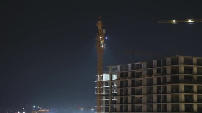 夜间建筑施工。延时。带有照明的建筑工地上的塔式起重机