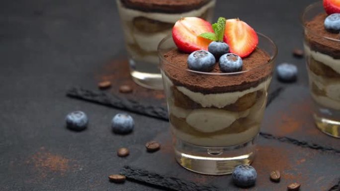 经典提拉米苏甜点，蓝莓和草莓放在混凝土上的石头上菜板上