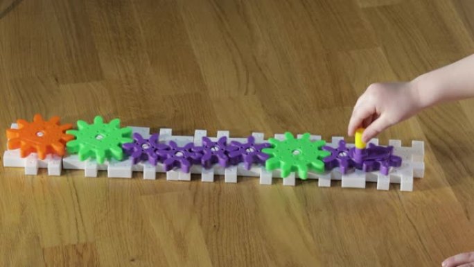 儿童手旋转彩色塑料齿轮的特写视图。儿童和游戏概念。