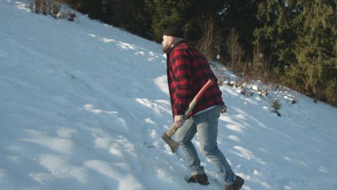 残酷的伐木工人带着斧头沿着雪坡走