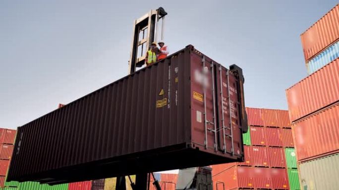 两名集装箱码头员工站在装运港的箱式集装箱上。