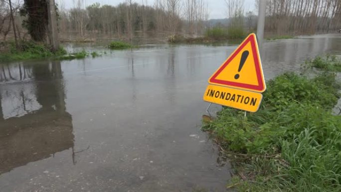 道路上的水，被河流和危险路标淹没的道路