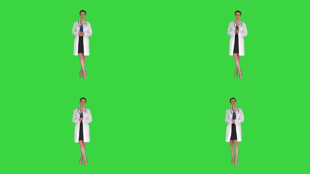 年轻的职业女性医生穿着制服，配有听诊器，在绿色屏幕上对着相机说话，色度键