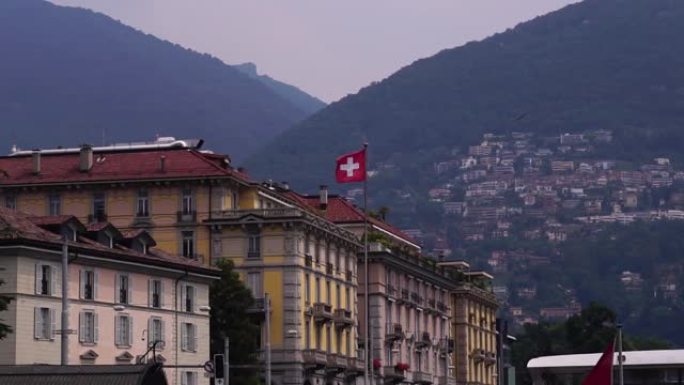 瑞士国旗。卢加诺湖建筑和蒙特布雷山。