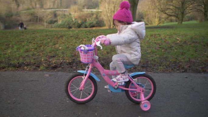 北爱尔兰冬季乡村公园的蹒跚学步的女孩骑自行车
