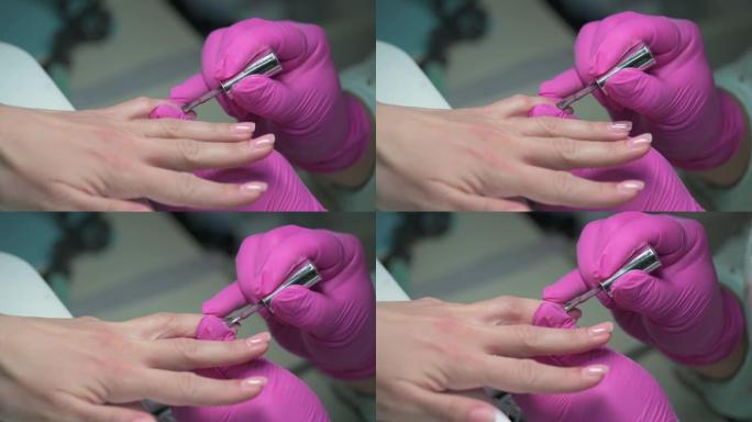 美甲美容师用闪光指甲油覆盖客户指甲的特写