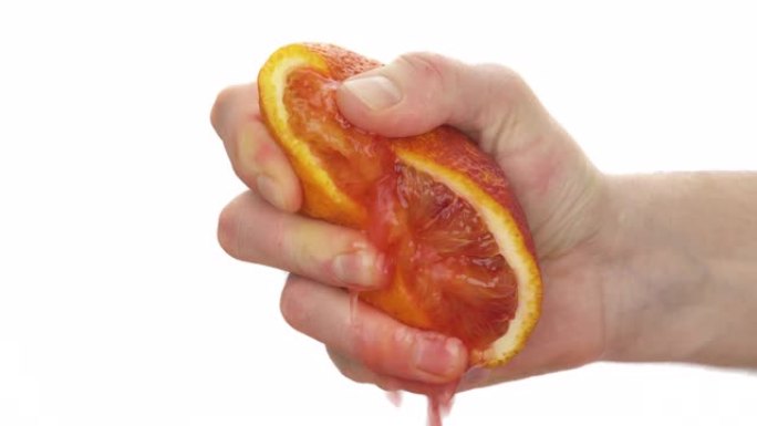 面目全非的人挤压一半血橙的特写。新鲜柑橘汁下降。孤立，在白色背景上