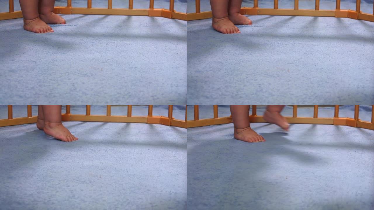 可爱的婴儿脚在游戏围栏的蓝色毯子上迈出第一步