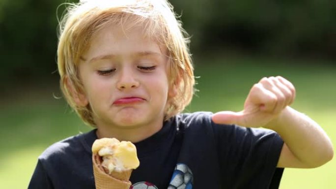 金发小男孩吃冰激丸，竖起大拇指