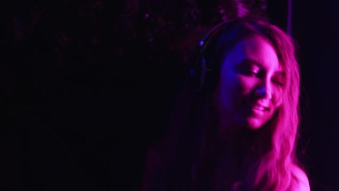 霓虹灯中的女孩用耳机享受音乐