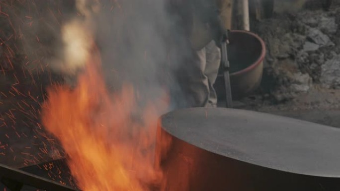 男子在木制高炉上加热一个大铜锅