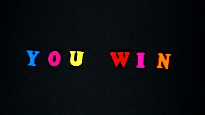由木制五彩字母组成的单词 “you win”。五颜六色的单词循环。