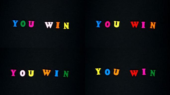 由木制五彩字母组成的单词 “you win”。五颜六色的单词循环。