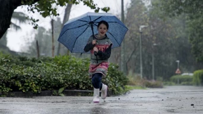 一个小女孩在水坑里跳伞的慢动作在雨中撑着伞