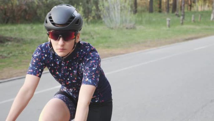年轻适合女子铁人三项运动员骑自行车训练。特写前方跟随镜头。铁人三项概念。