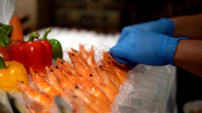 在海鲜餐厅，库克之手将新鲜的虾和牡蛎叠加在冰上。烹饪食谱。慢动作镜头。