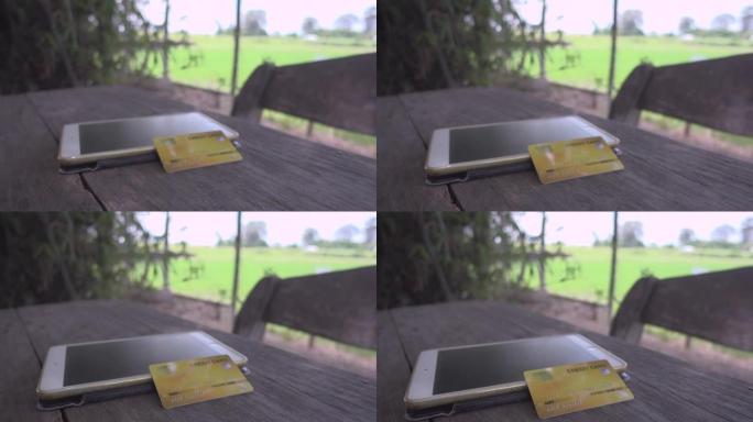 旧木桌多莉拍摄的带平板电脑的黄金信用卡