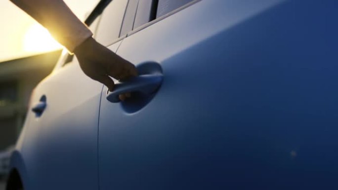 女人的手系统钥匙在驾驶慢动作前解锁车门，蓝色两厢车的车辆运输在街道上行驶。电影镜头