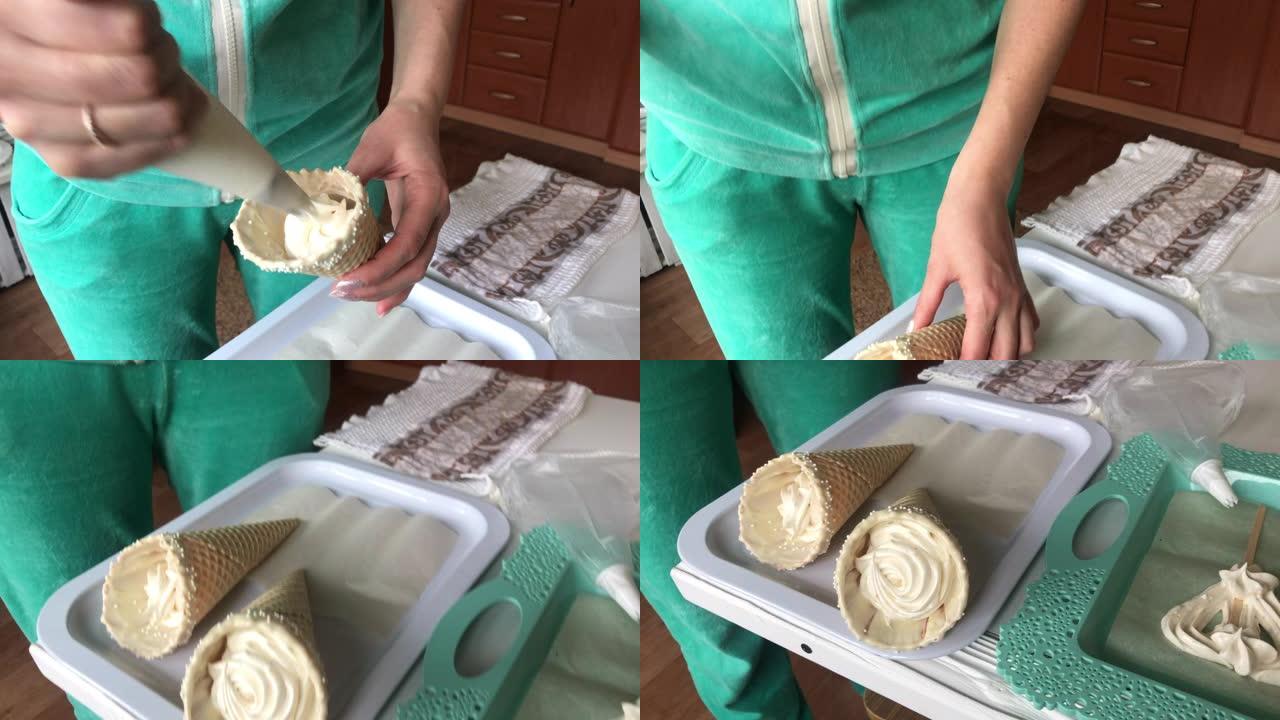 烹饪棉花糖。一名妇女使用糕点袋和喷嘴在华夫饼蛋筒中填充棉花糖。把它放在托盘上。