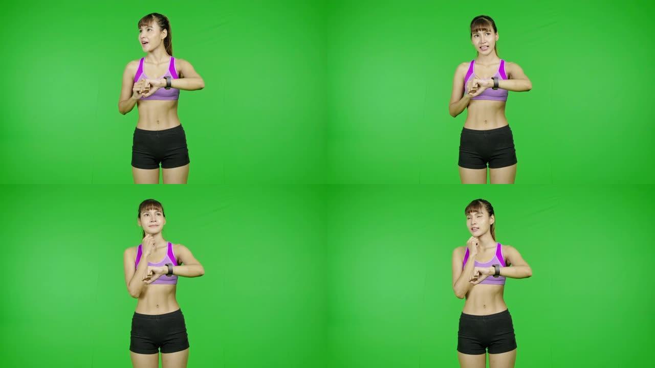 健康女性使用智能手表为她健身，绿色屏幕，专注设置，环顾四周，惊喜，为卤素效果。亚洲女运动员站在镜头前