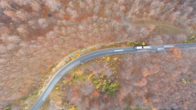 无人机在蜿蜒的道路上跟随汽车和卡车穿过森林