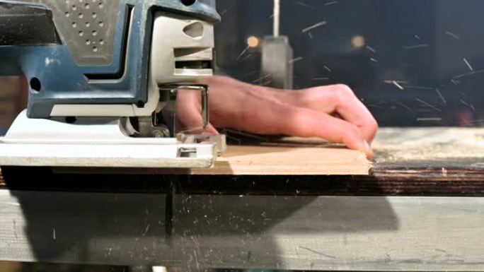 男性木匠的手在他的家庭车间里用作电动拼图。慢动作切割木制零件
