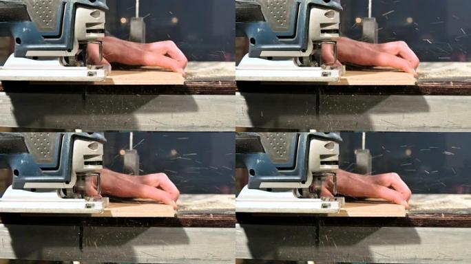 男性木匠的手在他的家庭车间里用作电动拼图。慢动作切割木制零件