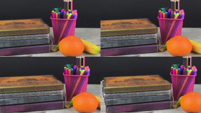 学校午休的概念，香蕉，橘子和木制课桌上的学校用品，有选择的重点。强调这一概念的书籍、记号笔和彩色铅笔