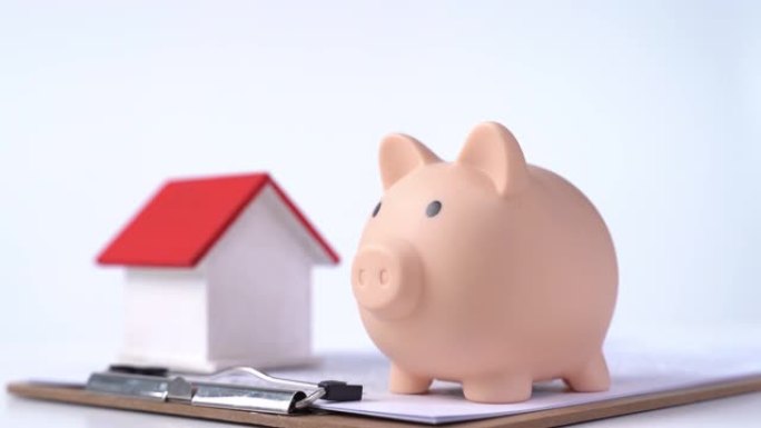存钱罐，漂亮的木屋模型在白色背景上签订了合同，省钱的概念购买了房屋保险。