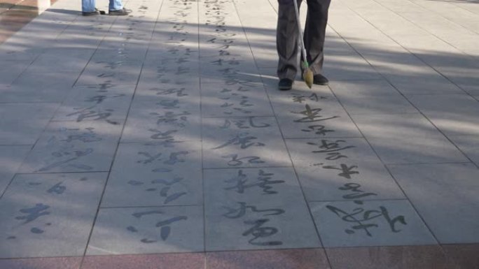 在中国甘肃张掖，人们用毛笔在地上书写佛经。