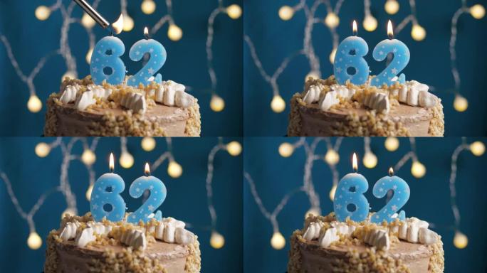 蓝色背景上有62号蜡烛的生日蛋糕。蜡烛着火了。慢动作和特写视图