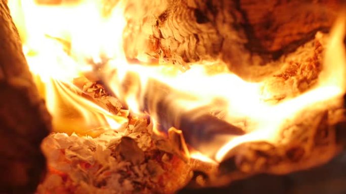 树在壁炉里燃烧得很漂亮。雄性手把柴火放在炉子里。壁炉里燃烧着火。4K.中等火焰壁炉环夹