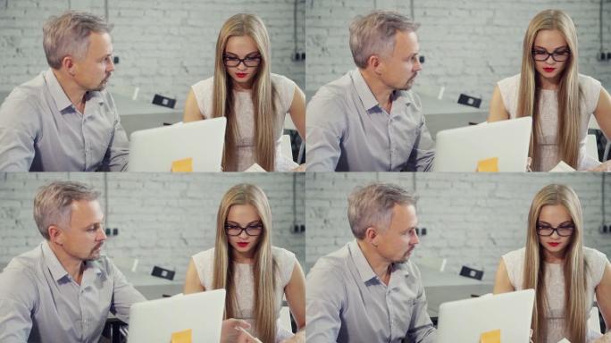 男人和女人在办公室里用笔记本电脑在餐桌上聊天
