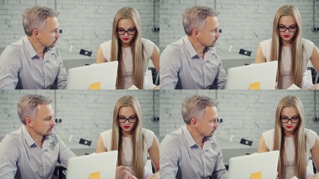 男人和女人在办公室里用笔记本电脑在餐桌上聊天