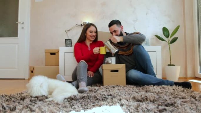 幸福的夫妇坐在他们新公寓的地板上喝咖啡