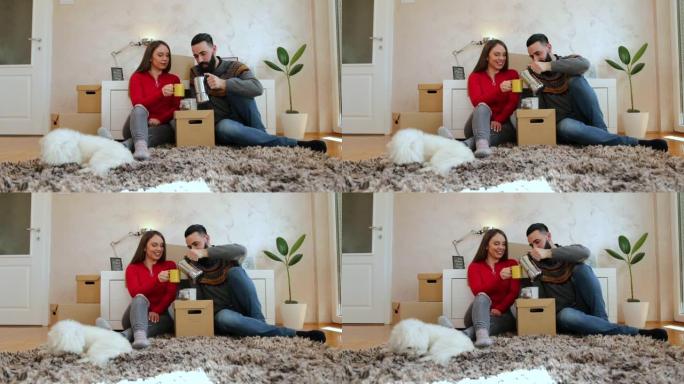 幸福的夫妇坐在他们新公寓的地板上喝咖啡