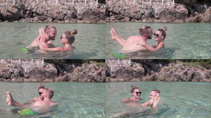 年轻夫妇在黑山美丽的海滩上在浅水中笑和玩耍