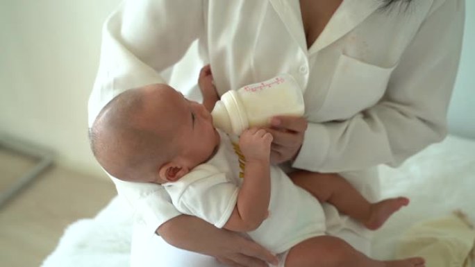 母亲在家中用奶瓶抱着并喂养一个新生的男婴。孩子似乎以后拒绝喝酒
