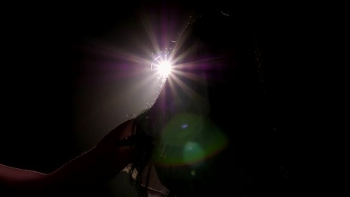 在聚光灯下，一个女孩在舞台上戴着麦克风的剪影。