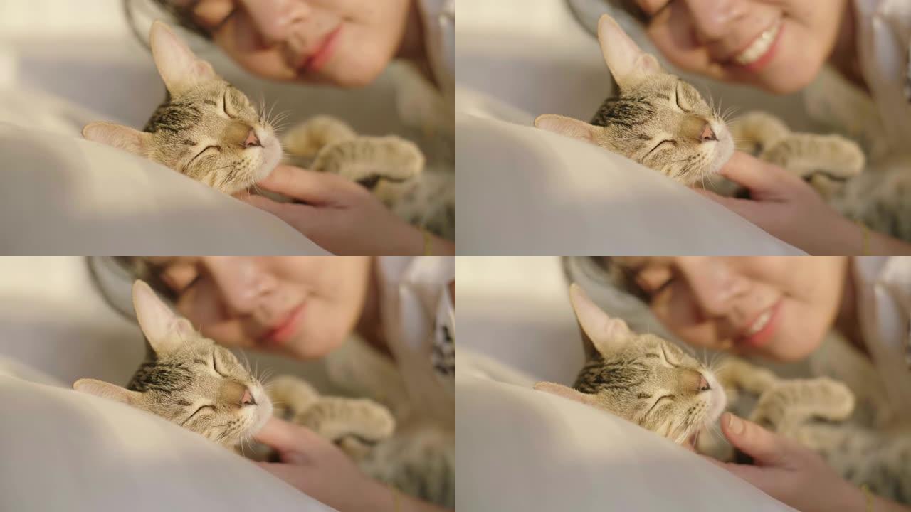 年轻女子在卧室的白色床上亲吻她的宠物小猫。