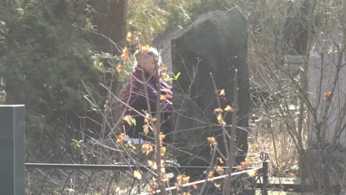 在墓地探望坟墓的老年妇女。辛菲罗波尔的阿布达尔公墓。