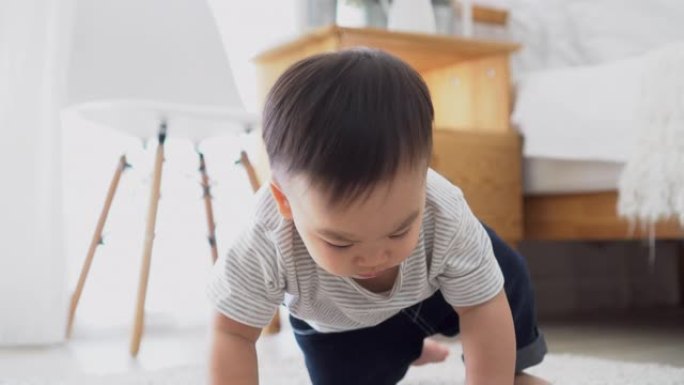 男婴在室内客厅的地板上爬行。蹒跚学步的亚洲家庭独自在家