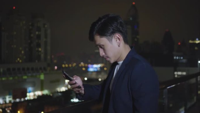 亚洲男子在午夜街头城市使用智能手机，绝望，失望