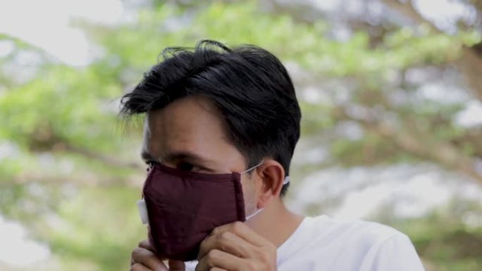 慢动作年轻亚洲男子戴防护口罩防止病菌和空气污染，保健理念