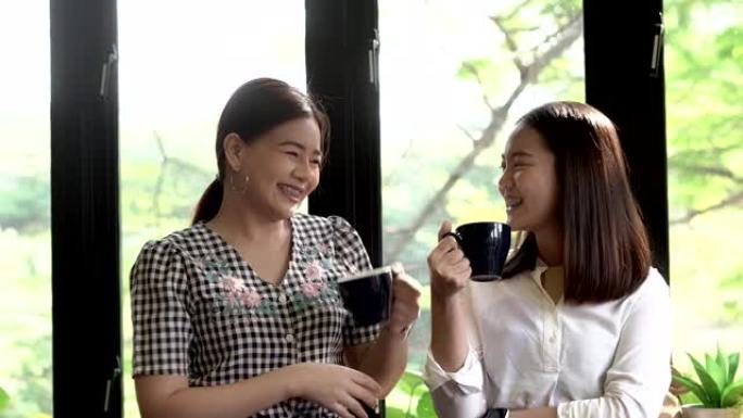 两个漂亮快乐的女孩站着说话，边喝鸡尾酒或咖啡