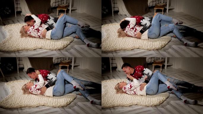 一对恋爱中的年轻夫妇在床边的地板上热情地拥抱在家里。