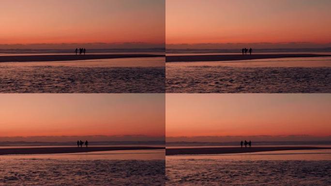 在金色的日落/日出上进行了一次惊人的冲浪之后，三个冲浪者从海上出来的惊人照片。