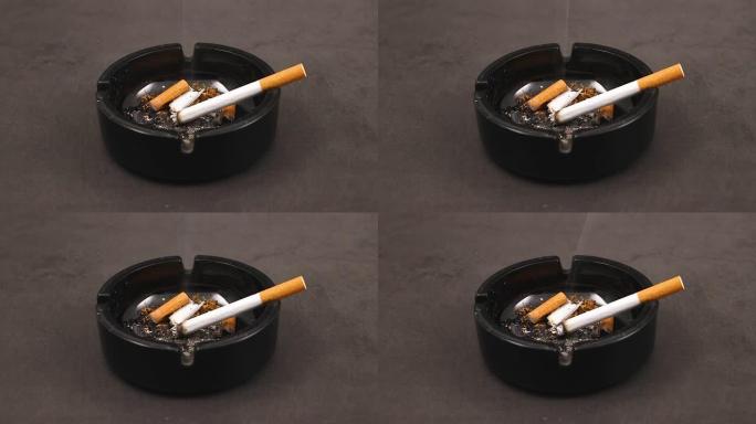 在装满烟头的黑色烟灰缸中燃烧香烟